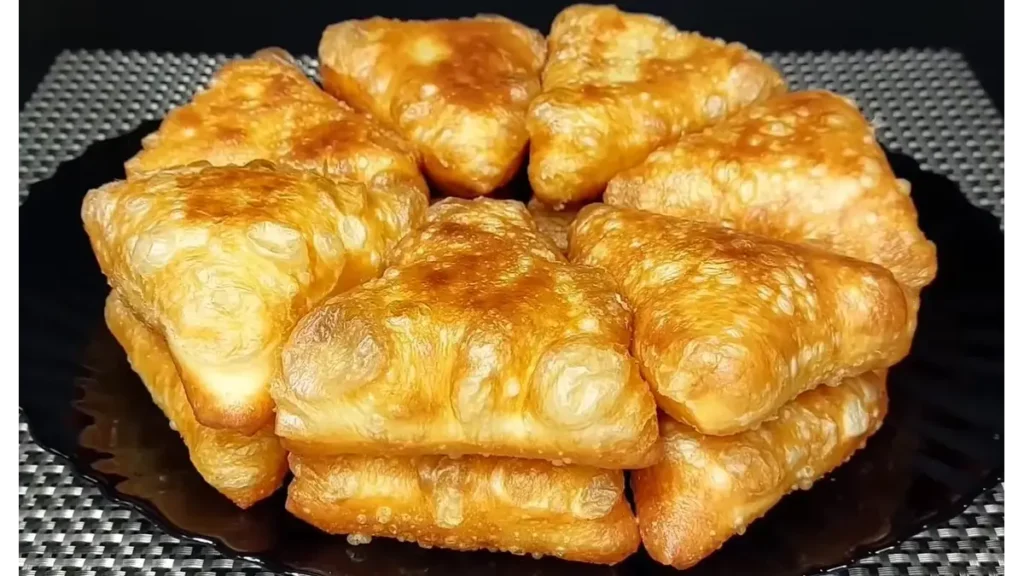 Golden fried kefir potato puffs filled with savory potato mixture, arranged on a black plate.